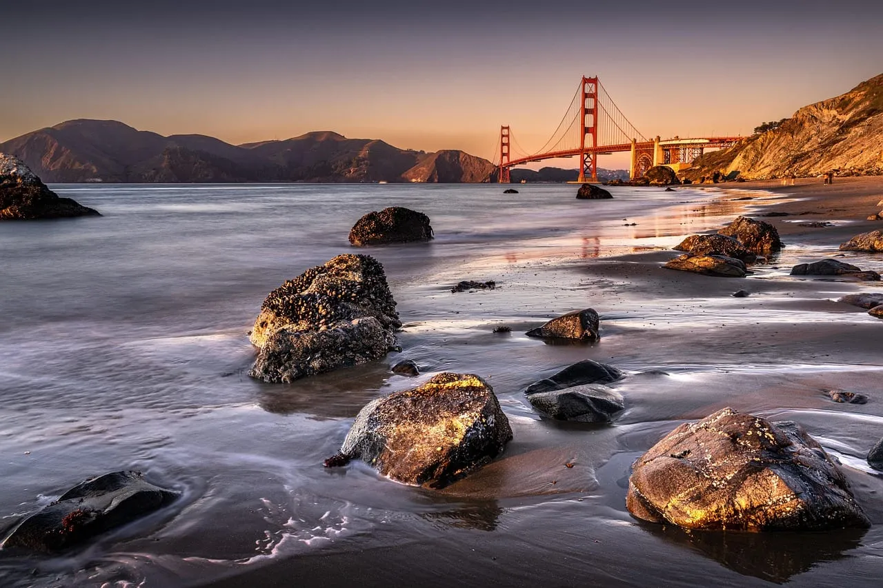Le pont vu depuis une plage rocheuse au coucher du soleil