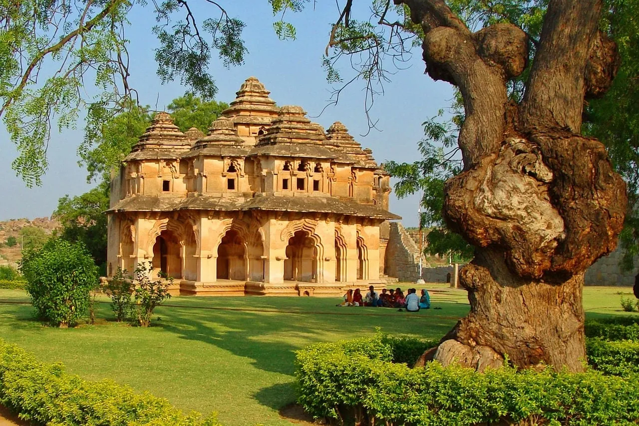 Le Lotus Mahal et ses arcs étagés, à côté d’un grand arbre ancien