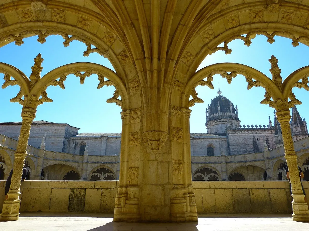 Le cloître vu à travers un arc sculpté, la coupole en arrière-plan