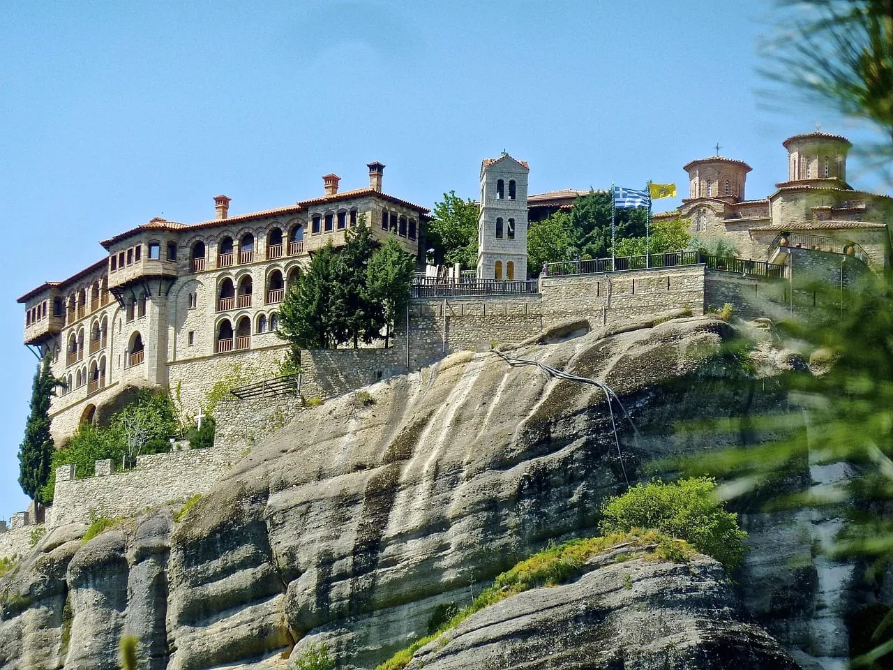 Un grand monastère avec un clocher sur une corniche rocheuse
