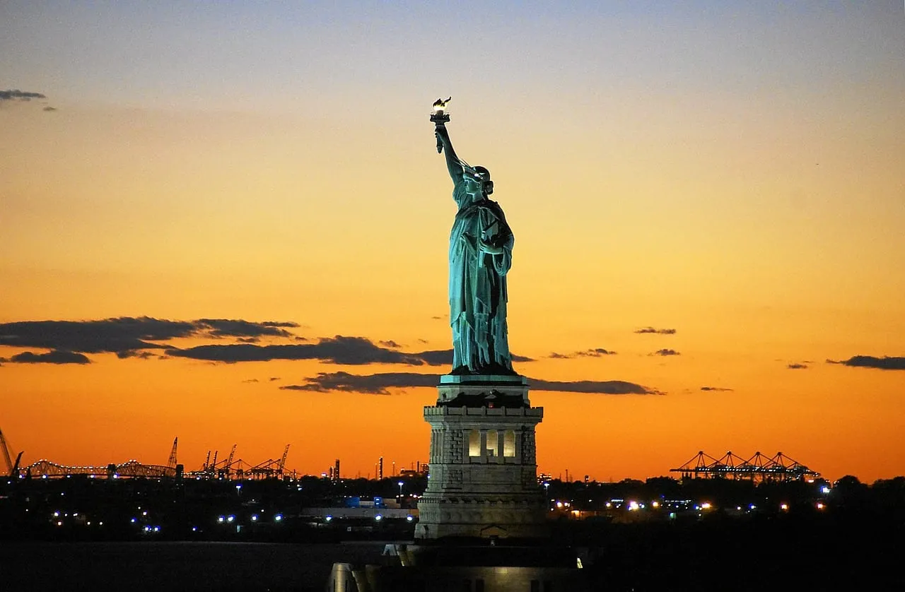 La statue de la Liberté se découpant sur un coucher de soleil orange