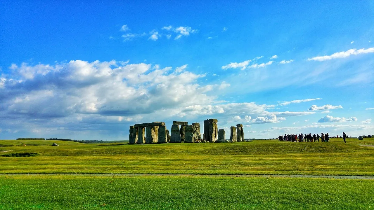 Le cercle de pierres vu de loin, au-delà d’une vaste étendue d’herbe, avec des visiteurs sur le chemin