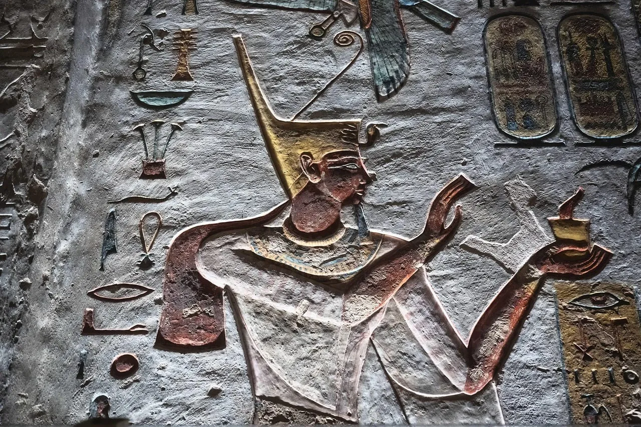 Un roi sculpté et peint faisant une offrande, entouré de hiéroglyphes